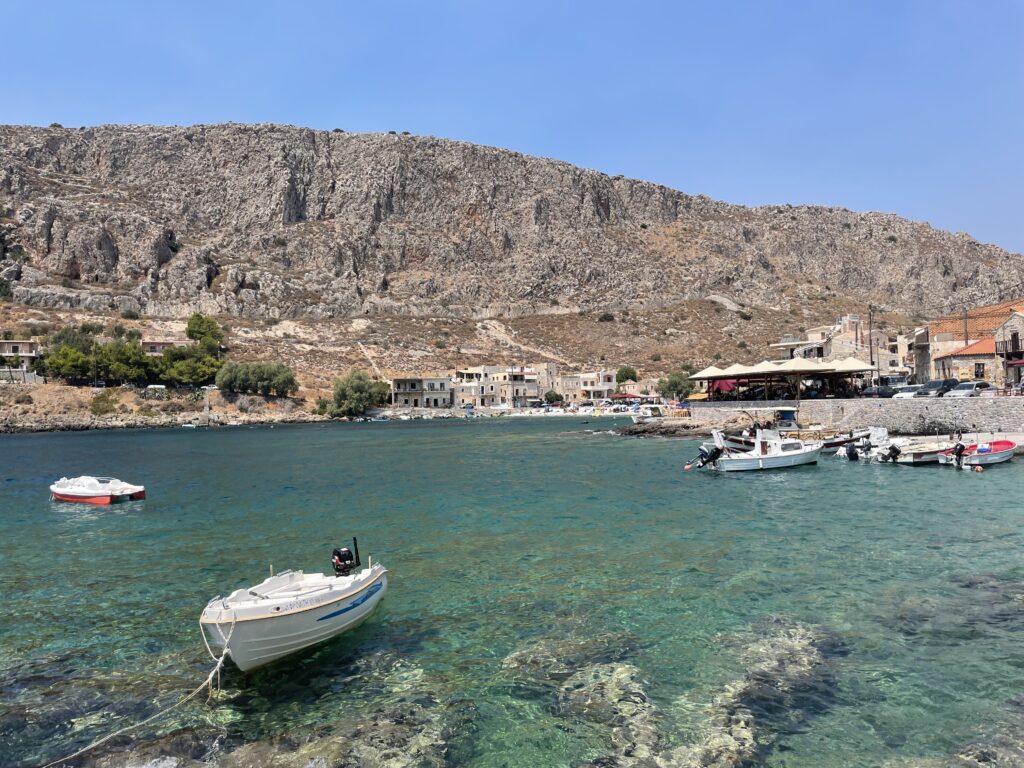 Small boats float on crystal clear waters in the Deep Mani