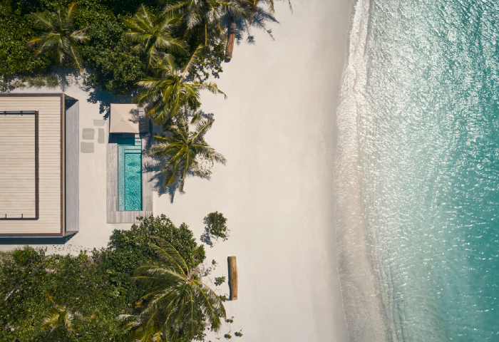 A birds eye view of Patina Maldives' pool and palm-lined shore